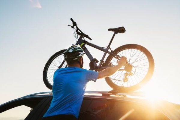 Mountain biker man takes of his bike from the car roof